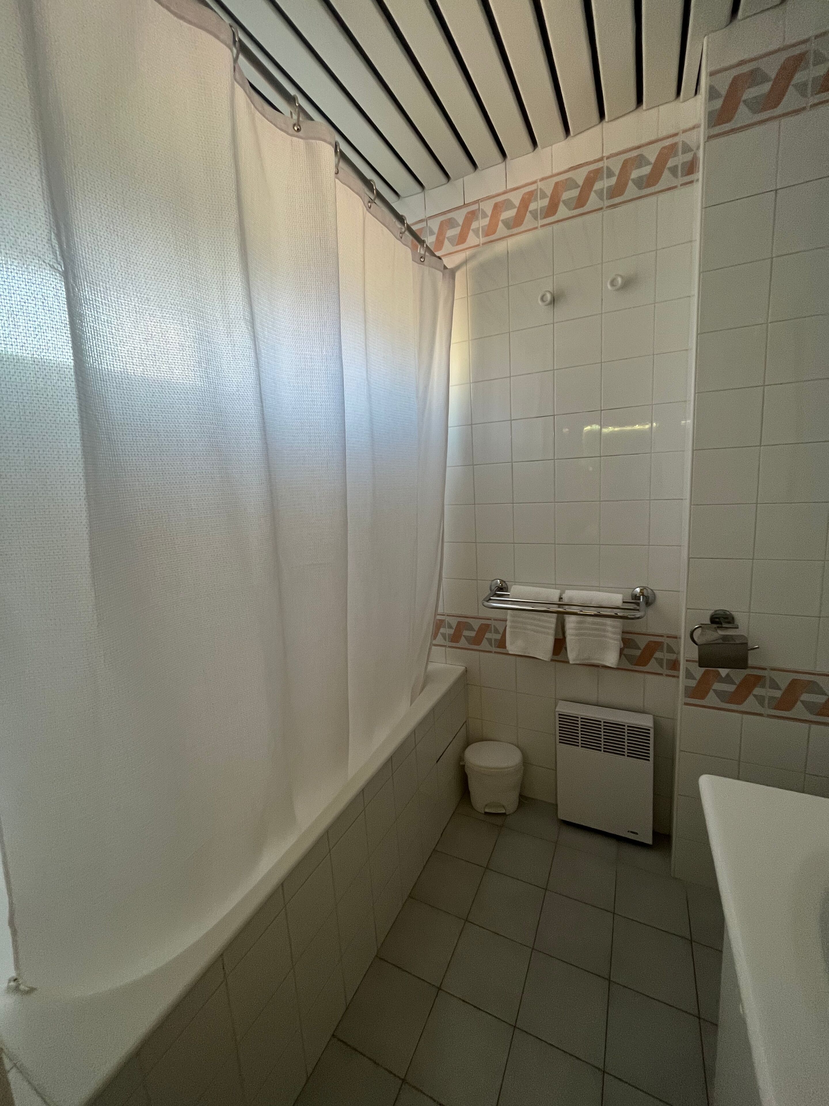 A small, tiled bathroom with a shower, a toilet, and a sink.