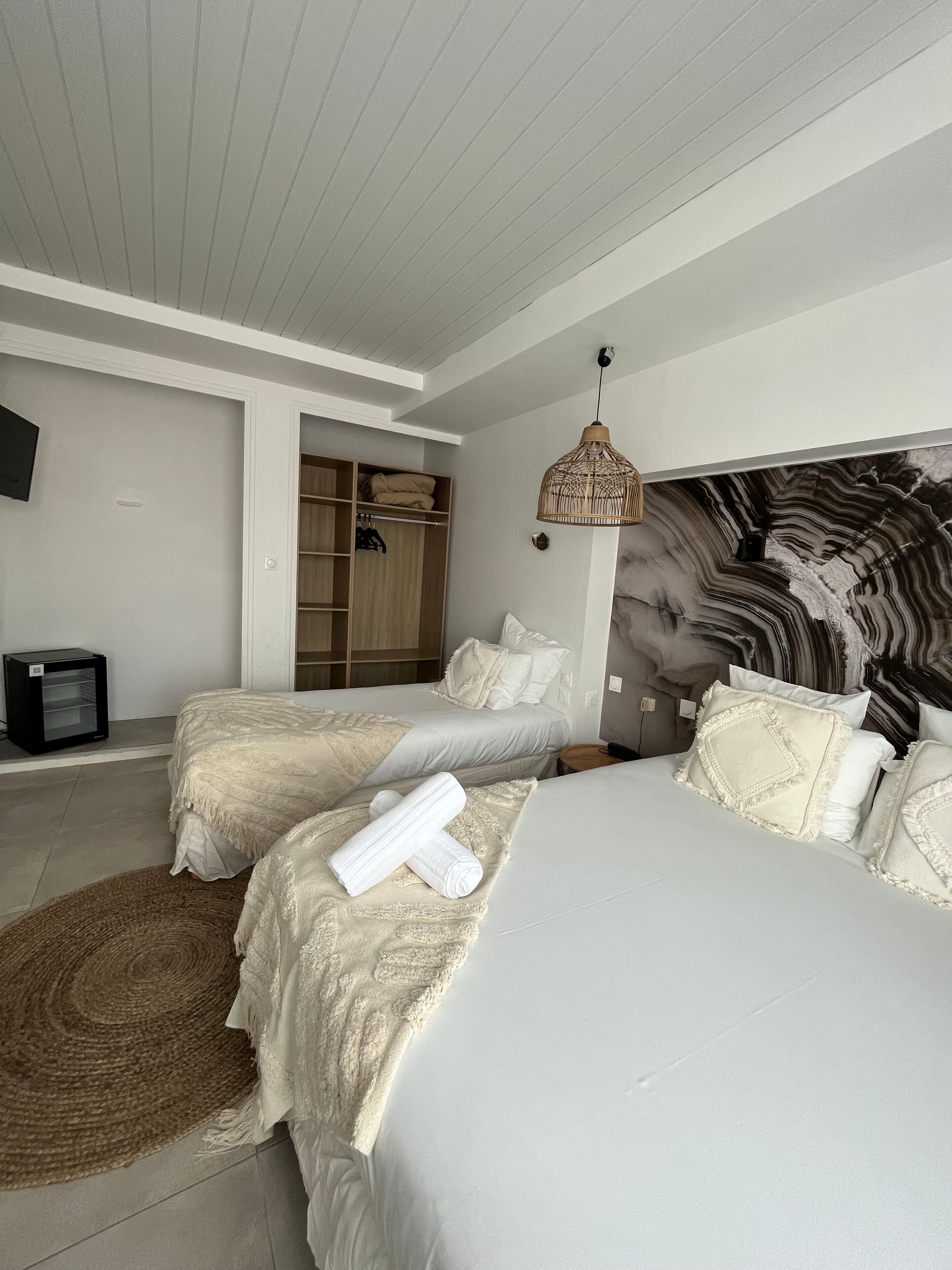 Une chambre avec deux lits, une armoire, un téléviseur et une tête de lit décorative.