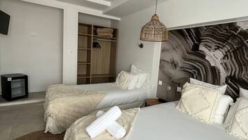 Une chambre avec deux lits, une armoire, un téléviseur et une tête de lit décorative.