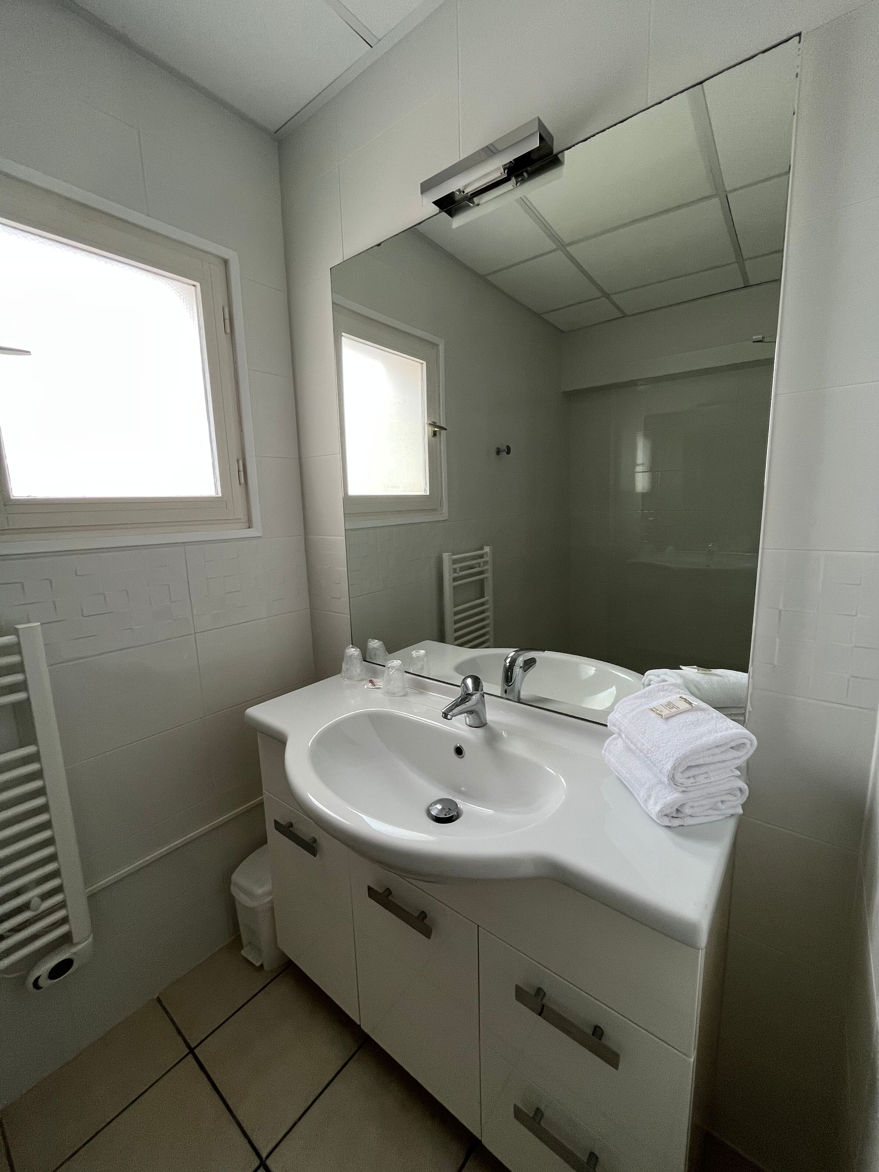 A bathroom with a white sink, mirror, and a window.
