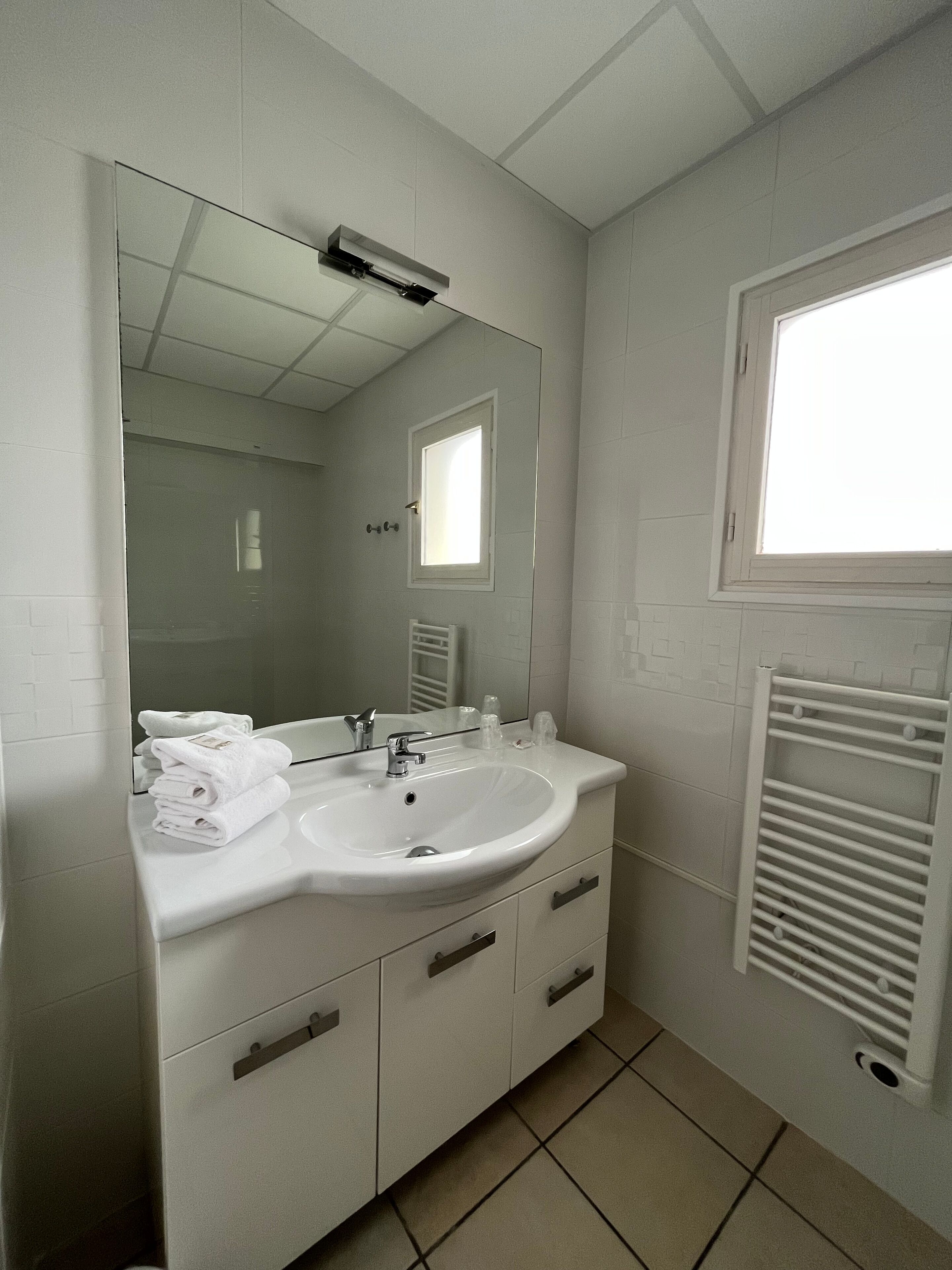 A bathroom with a white sink, mirror, and towel rack.