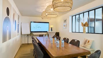 Une salle de conférence équipée d’une longue table, de chaises, d’un écran de projection et d’éléments décoratifs.
