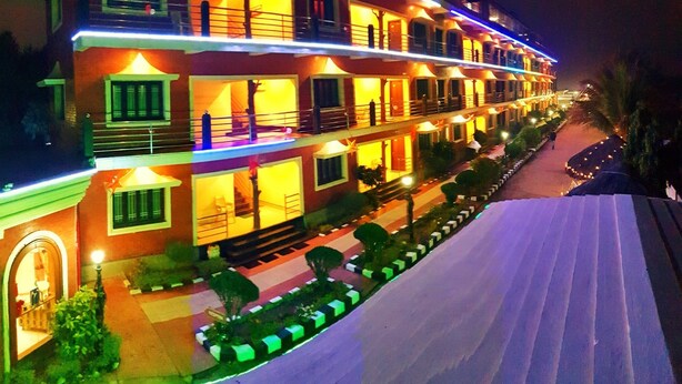 A multi-story hotel with balconies, a central courtyard, and a well-lit facade. - Hotels Diamond Glory - Mandarmani (Kanthi)