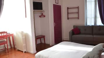 Une chambre à coucher avec un lit, une porte rouge, un canapé gris et une fenêtre avec des rideaux.