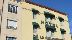Un hotel con un letrero que dice "HOTEL DE LA COLOMBIERE" y un letrero de "PARKING HOTEL" debajo.