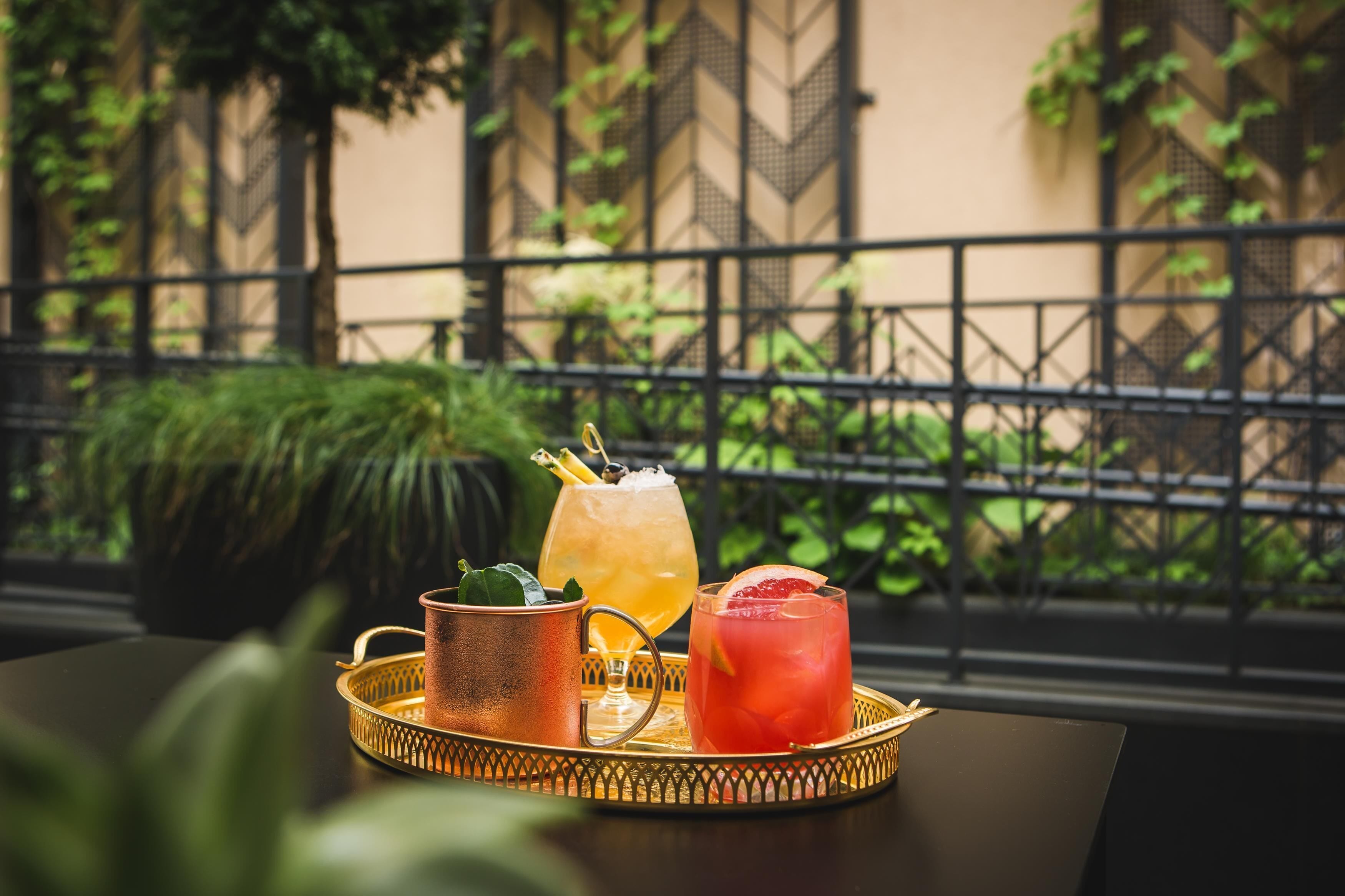 A tray with two drinks and a copper mug on a table.
