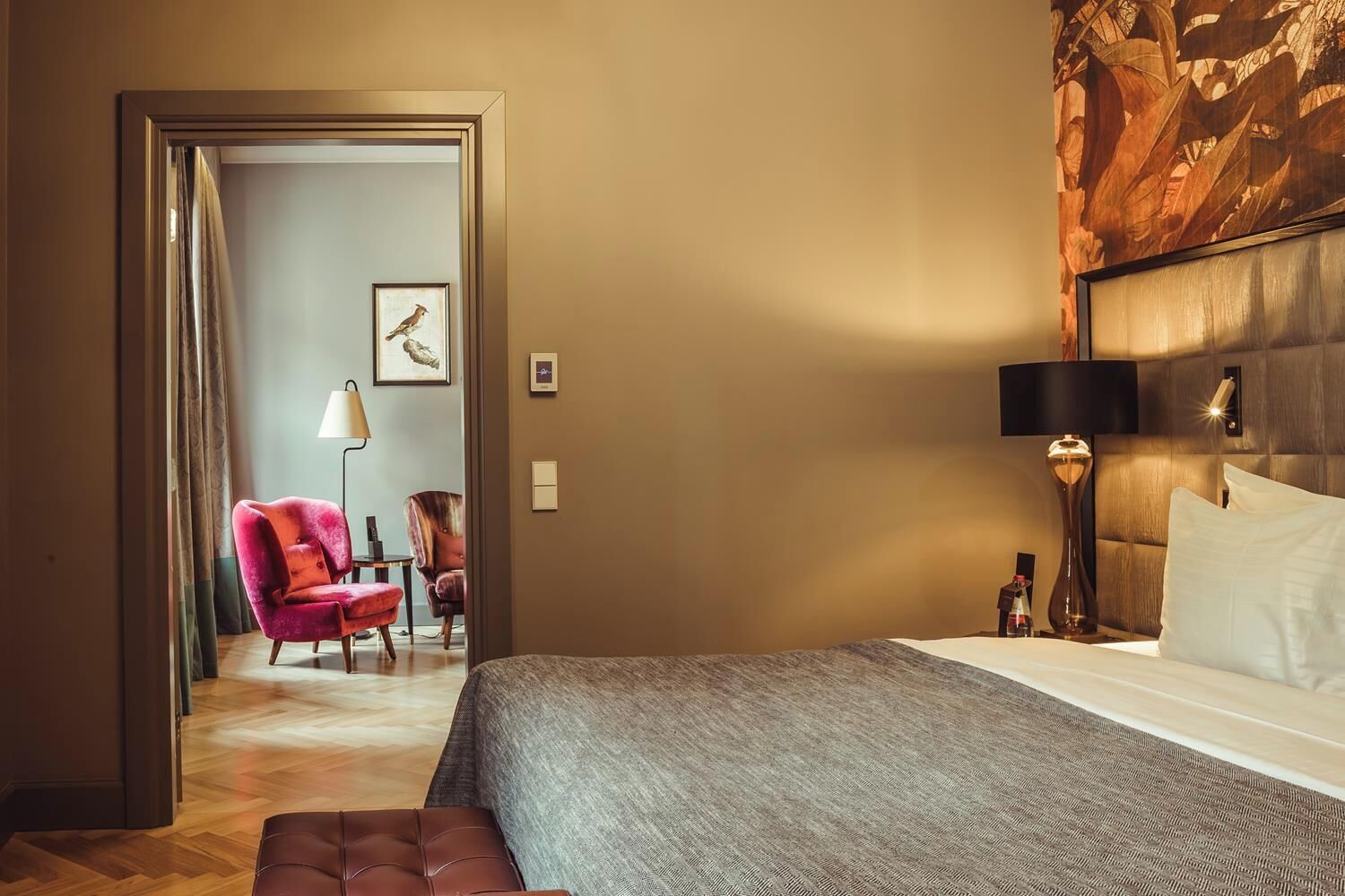 Et hotelværelse med en seng, et natbord, en lampe, en stol og et billede på væggen.