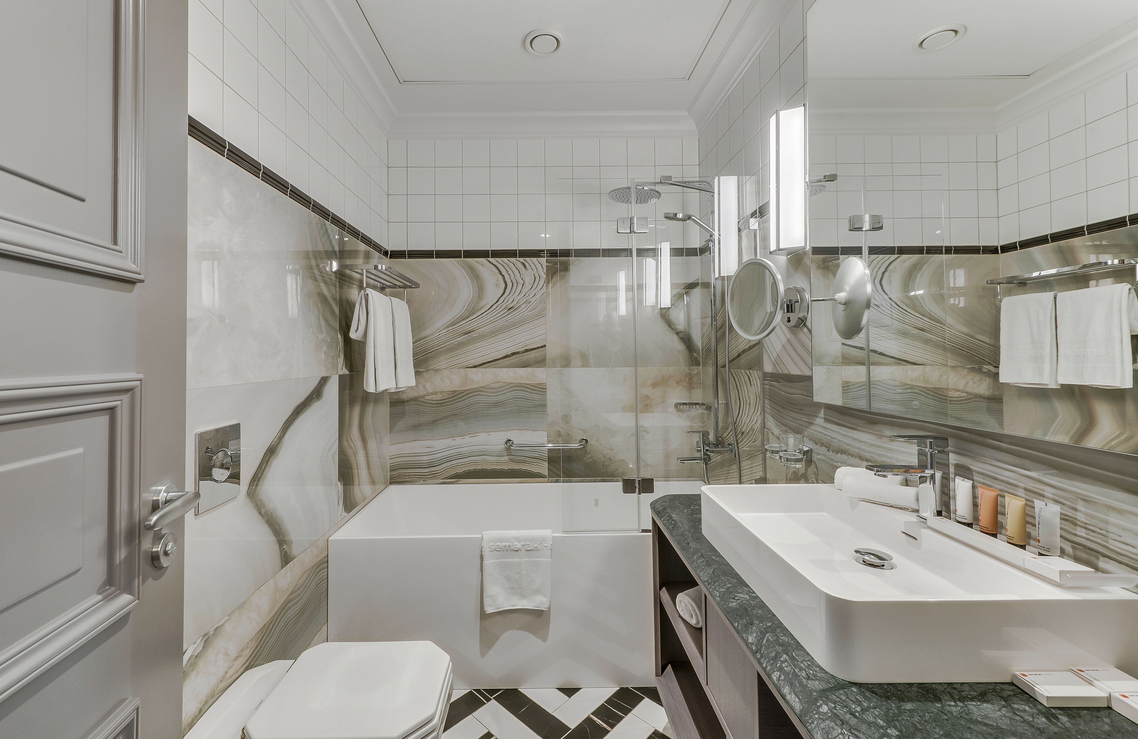 Un baño moderno con bañera, un espejo grande y un tocador con lavabo.