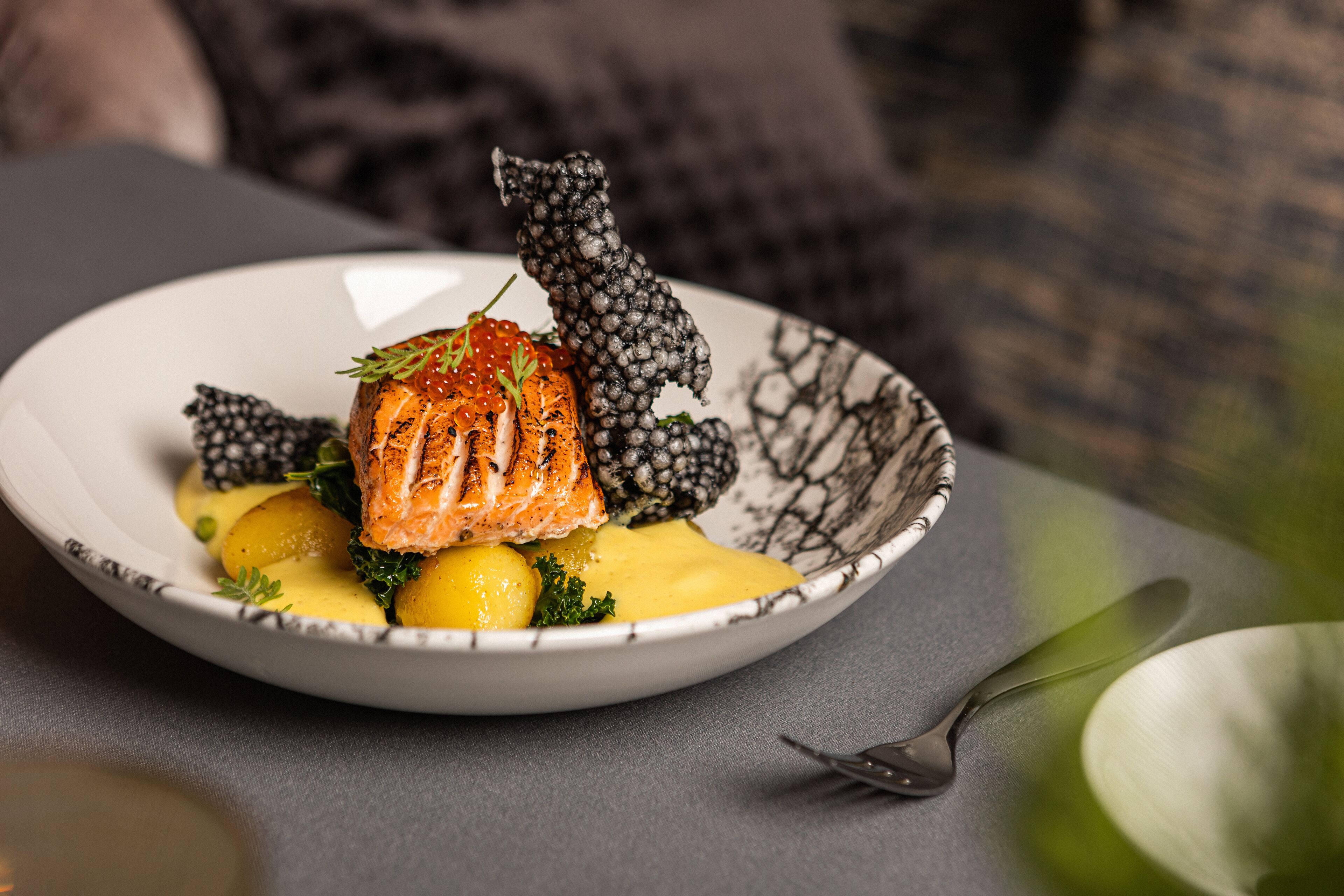 A plate of food with salmon, potatoes, and a decorative black and white pattern.