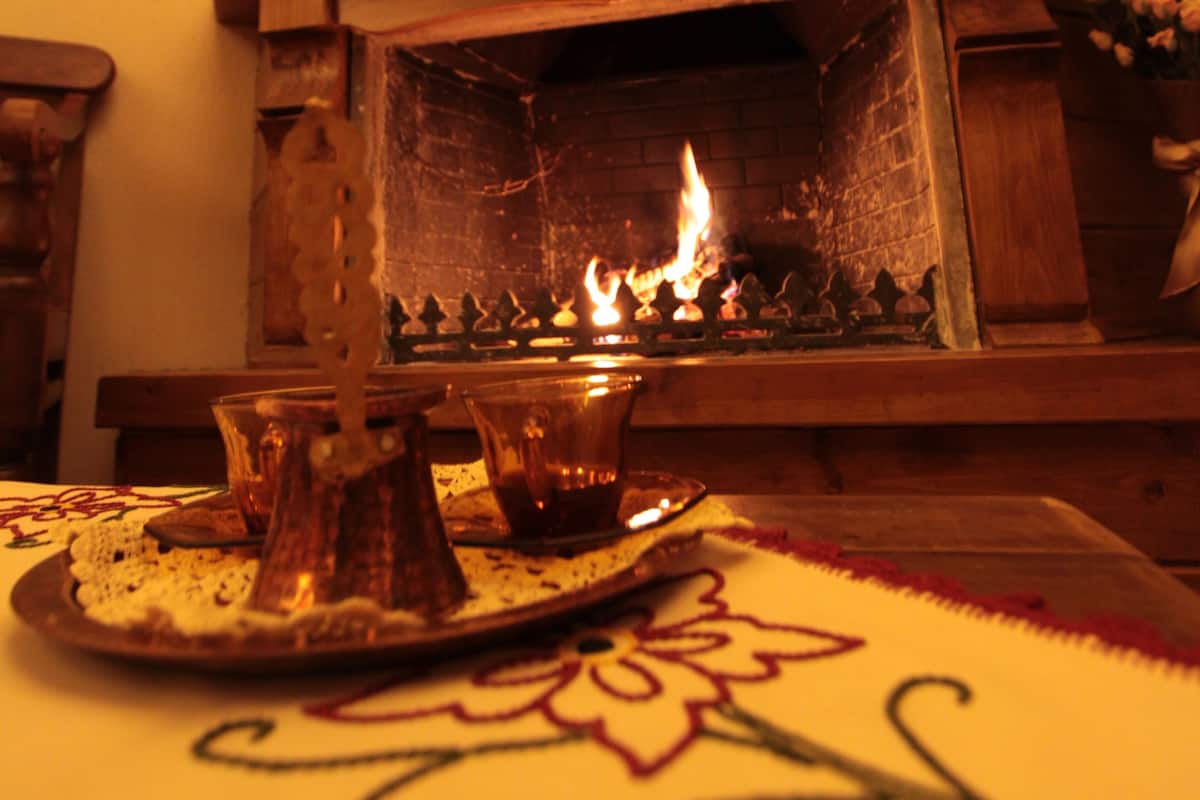 Una chimenea con fuego, una bandeja decorativa y una mesa con mantel estampado.