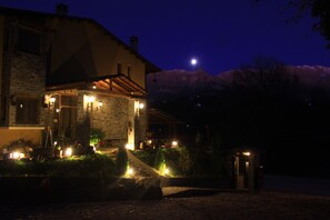 Una casa de piedra con techo inclinado y un porche iluminado por luces.