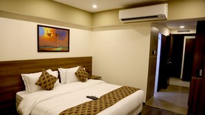 Una habitación de hotel con una cama grande, un cuadro en la pared y un equipo de aire acondicionado.