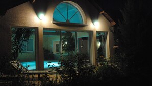 Une maison avec une piscine, de grandes fenêtres et un toit incurvé.