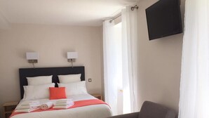 Une chambre d’hôtel avec un lit, une chaise, une télévision et des rideaux.