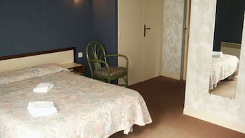 Un dormitorio con cama, una silla, una puerta y un espejo.