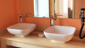 A bathroom with two white vessel sinks, a wooden vanity, a mirror, and a telephone.