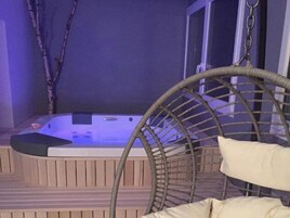 Un jacuzzi con muelle de madera y una silla de mimbre.