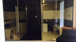 Une salle de bain moderne avec une douche à parois de verre, un banc en bois et des toilettes apparentes.