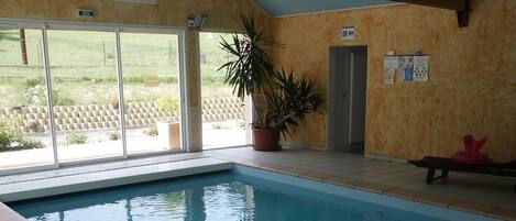Una piscina interior con puertas de cristal que dan a un espacio exterior.