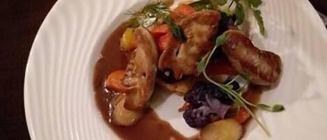 A plate of food with sausages, vegetables, and a sauce.