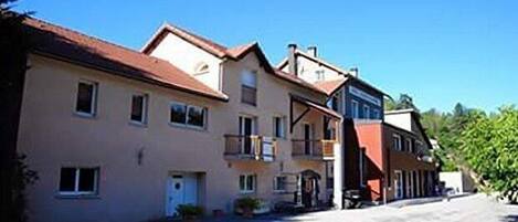 A row of two-story buildings with balconies, a clear sky, and a paved street.
