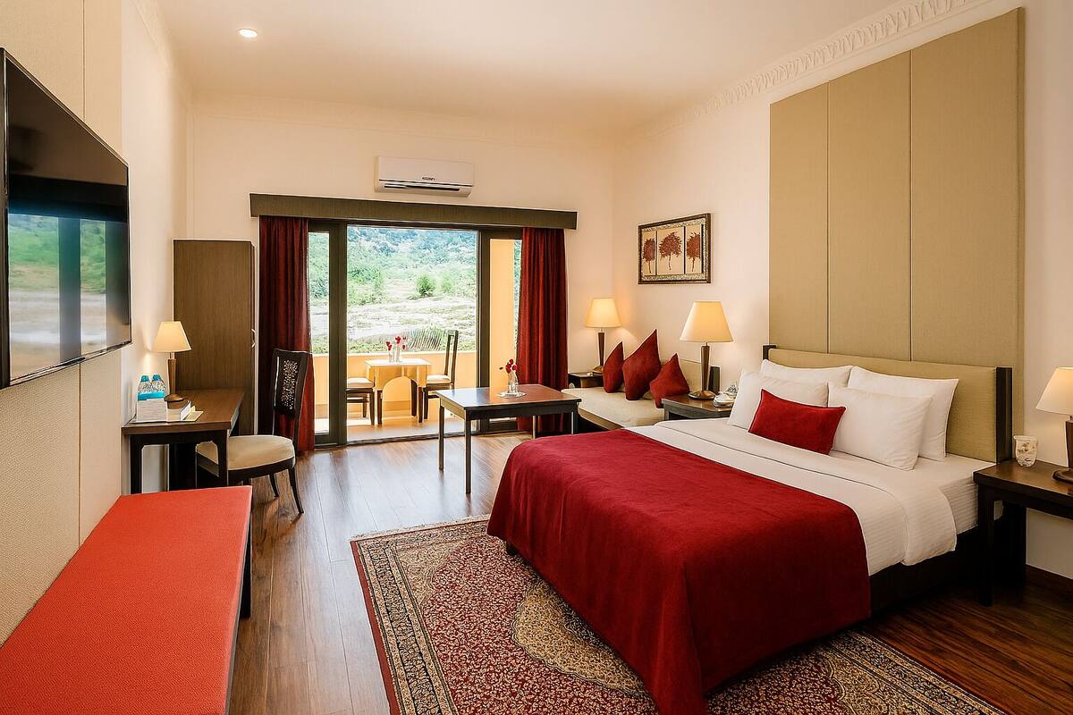 A hotel room with a bed, a desk, a chair, a table, and a view of the outdoors.