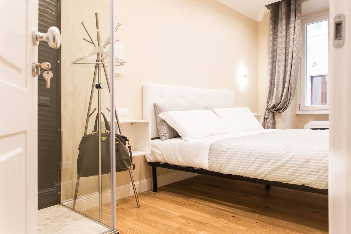 A bedroom with a bed, a coat rack, and a wardrobe.