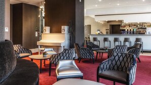 A modern lounge area with a piano, seating, and a bar with various bottles.