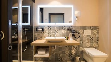 A modern bathroom with a large mirror, a sink, and a toilet.