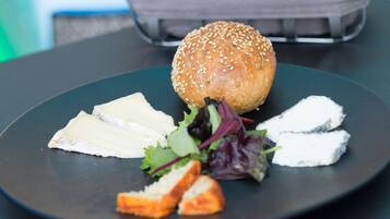 A plate with a sesame seed bun, cheese slices, and a small salad.