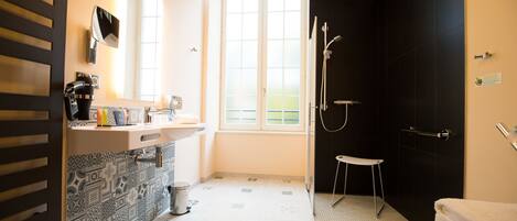 A modern bathroom with a sink, mirror, shower, and toilet.