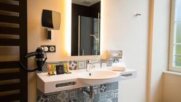 Een moderne badkamer met een grote spiegel, een haardroger en een wastafel met toiletartikelen.