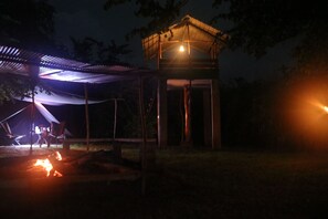 A gazebo with a roof, a small wooden structure, and a campfire. - Dev's Campground (Wellawaya)