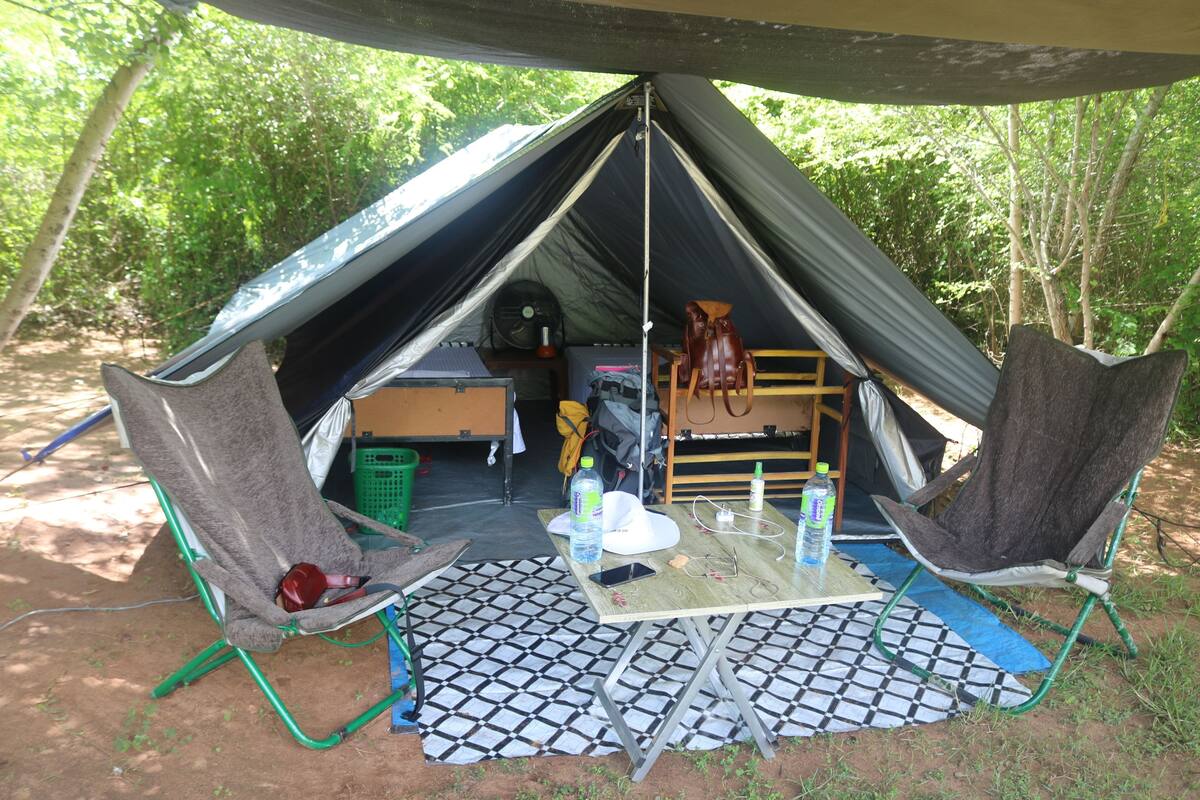 Una carpa con una mesa, sillas y una zona para dormir.
