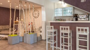 A modern kitchen with a bar area, white bar stools, and a clock on the wall. - Le Réverbère - La Cuisinerie - L'Hôtellerie (Vic-en-Bigorre)