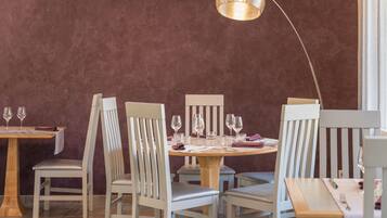 A dining area with a round table, white chairs, and a pendant light.