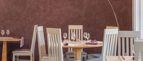 A dining area with a round table, white chairs, and a pendant light.