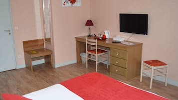 A bedroom with a bed, a desk, a chair, a television, and a small stool.