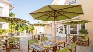 An outdoor patio area with multiple tables and chairs, each with a green umbrella. - Le Réverbère - La Cuisinerie - L'Hôtellerie (Vic-en-Bigorre)