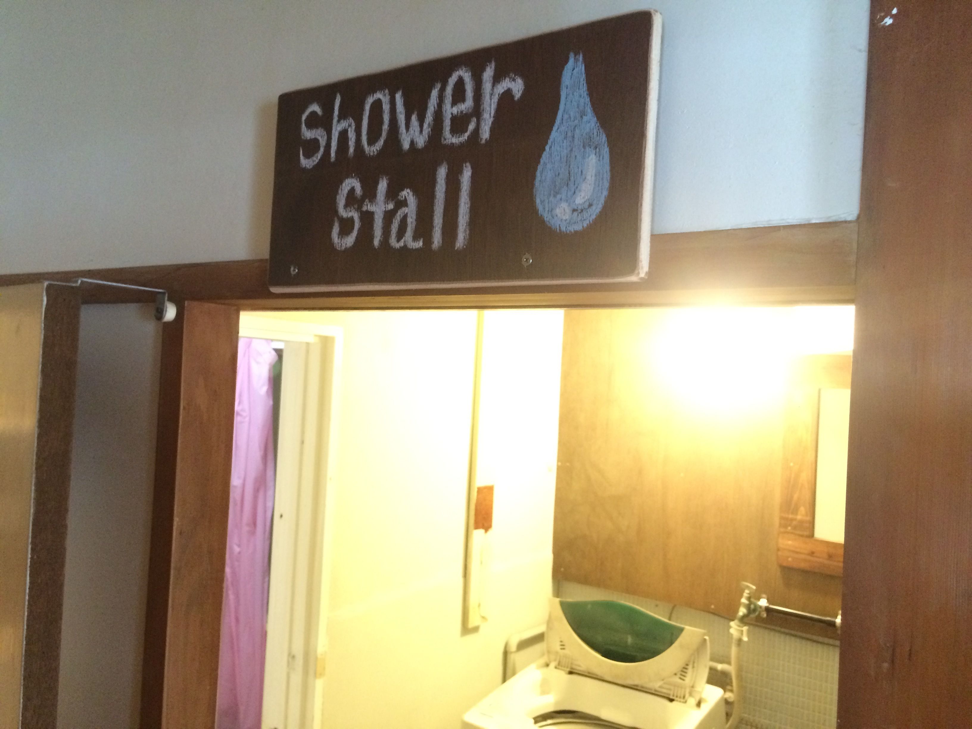 Un baño con un cartel sobre el espejo que dice 'cabina de ducha' y un símbolo de gota de agua.