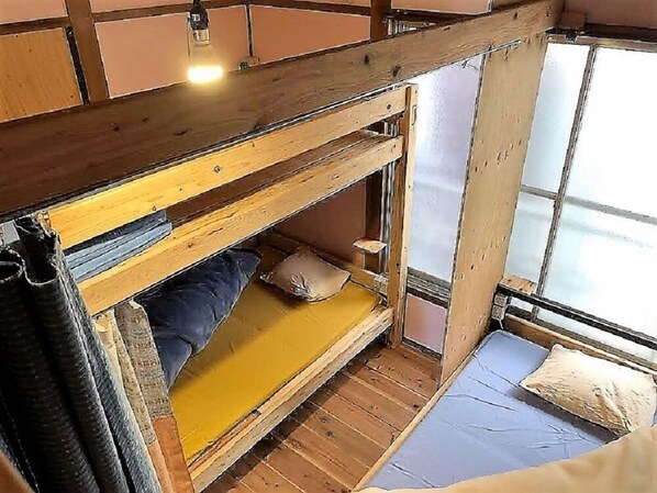 Habitación con literas, techo de madera, una ventana y una cortina.