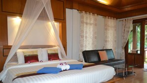 Une chambre bien aménagée, dotée d’un grand lit, d’une table de chevet, d’une chaise et de rideaux.