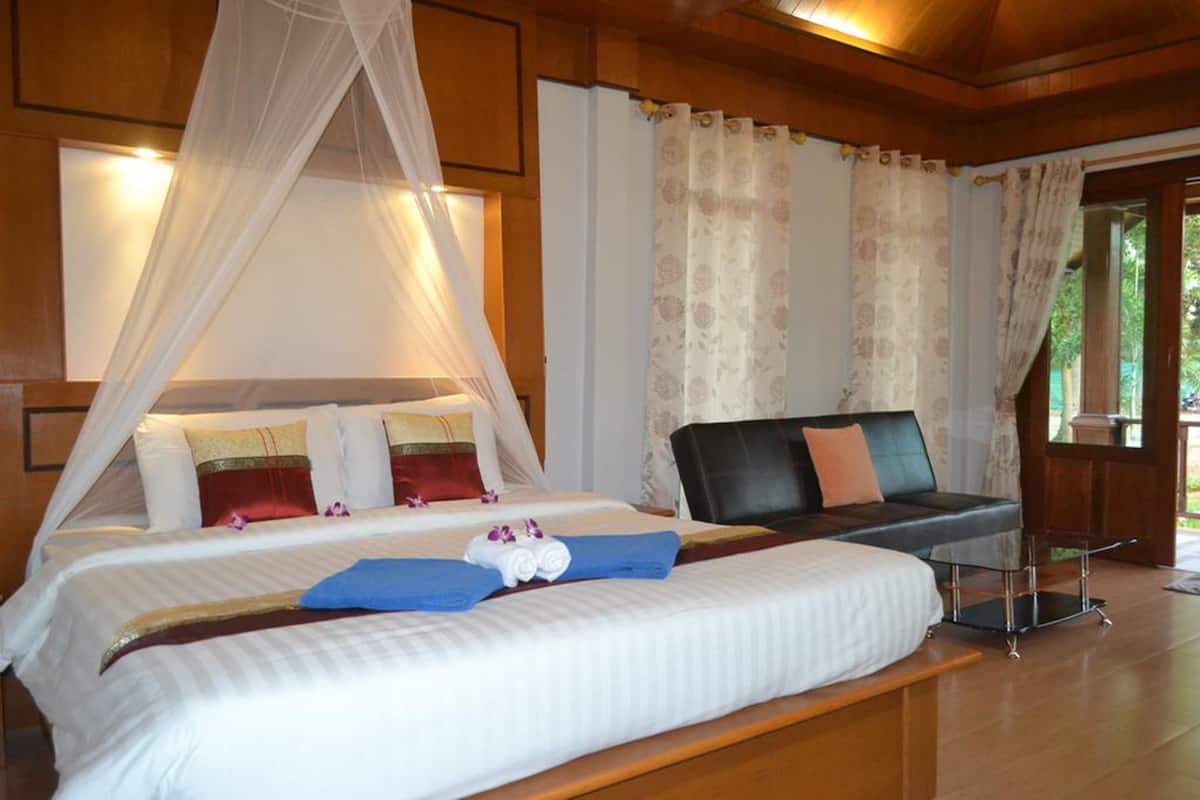 A well-appointed bedroom with a large bed, a bedside table, a chair, and curtains.