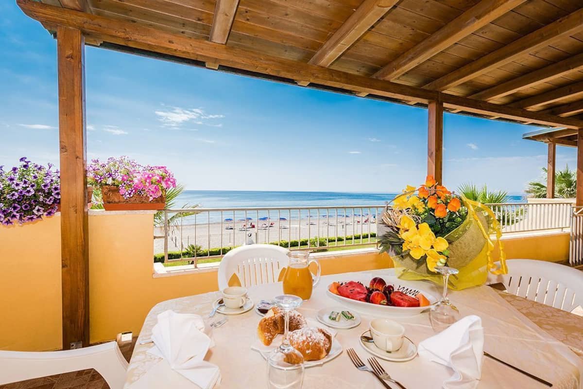Une table dressée pour le petit-déjeuner, avec vue sur la plage et l’océan.