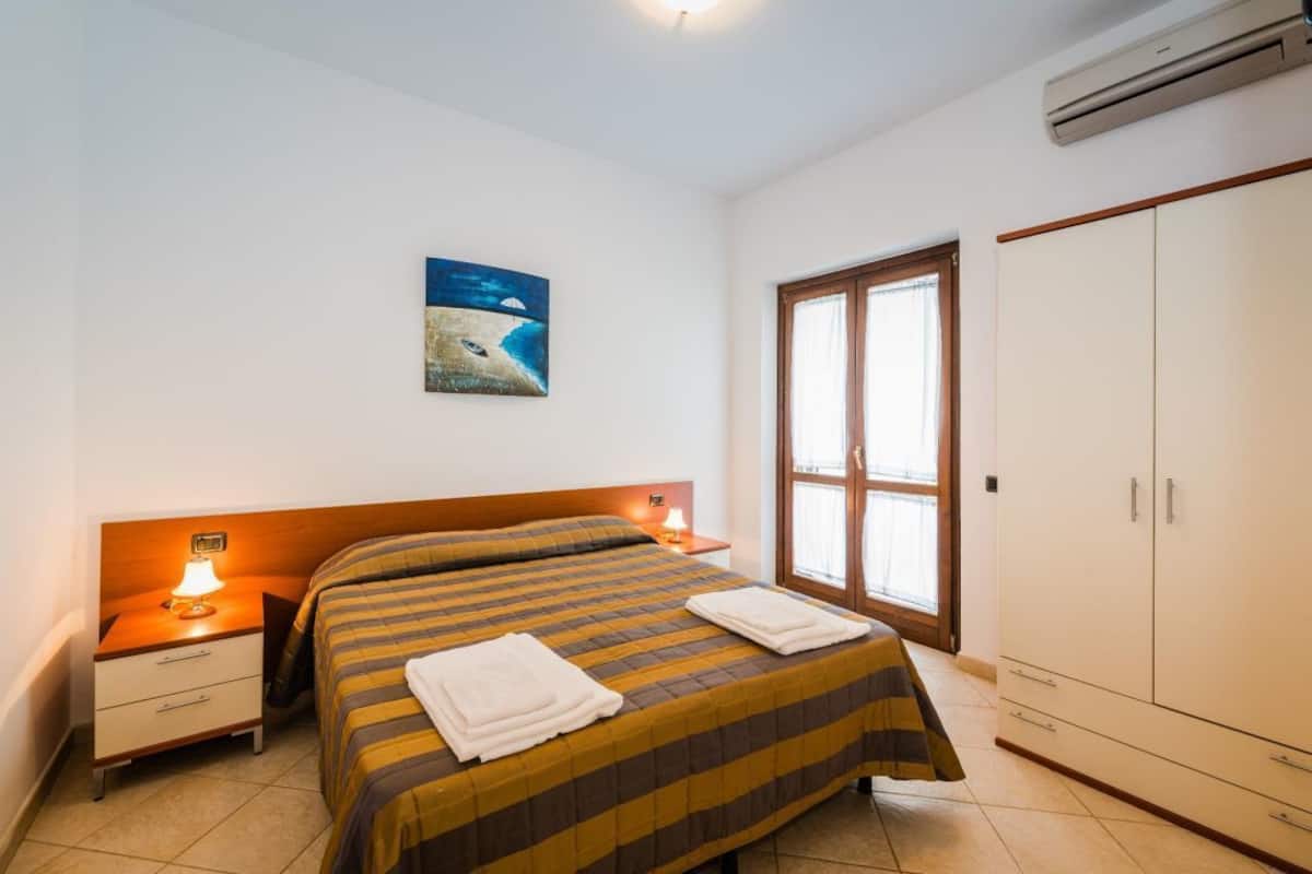 Une chambre à coucher avec un lit, des tables de chevet, une armoire et un tableau au mur.