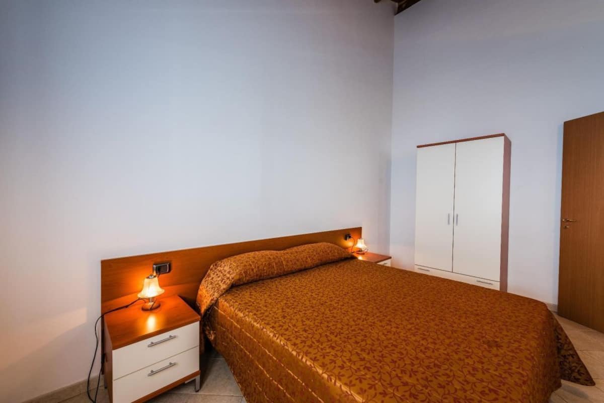 Une chambre à coucher avec un lit, des tables de chevet, une armoire et une lampe.
