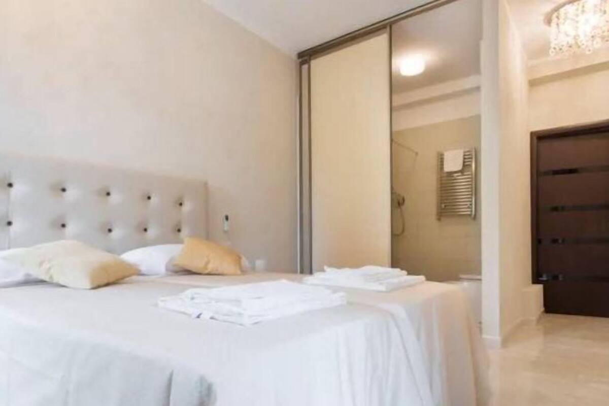 A bedroom with a large bed, a wardrobe, and a bathroom visible through an open door.