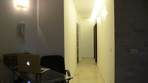 Ein Hotelzimmer mit Glastisch, Laptop, Stuhl und Wandtelefon.