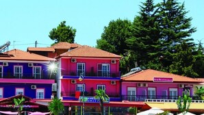 Un hôtel situé en bord de mer, avec des bâtiments aux couleurs vives, une plage de sable et des parasols.