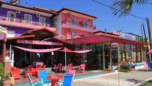 Un hôtel aux couleurs vives, doté d’une terrasse et d’une enseigne de restaurant bien visible.